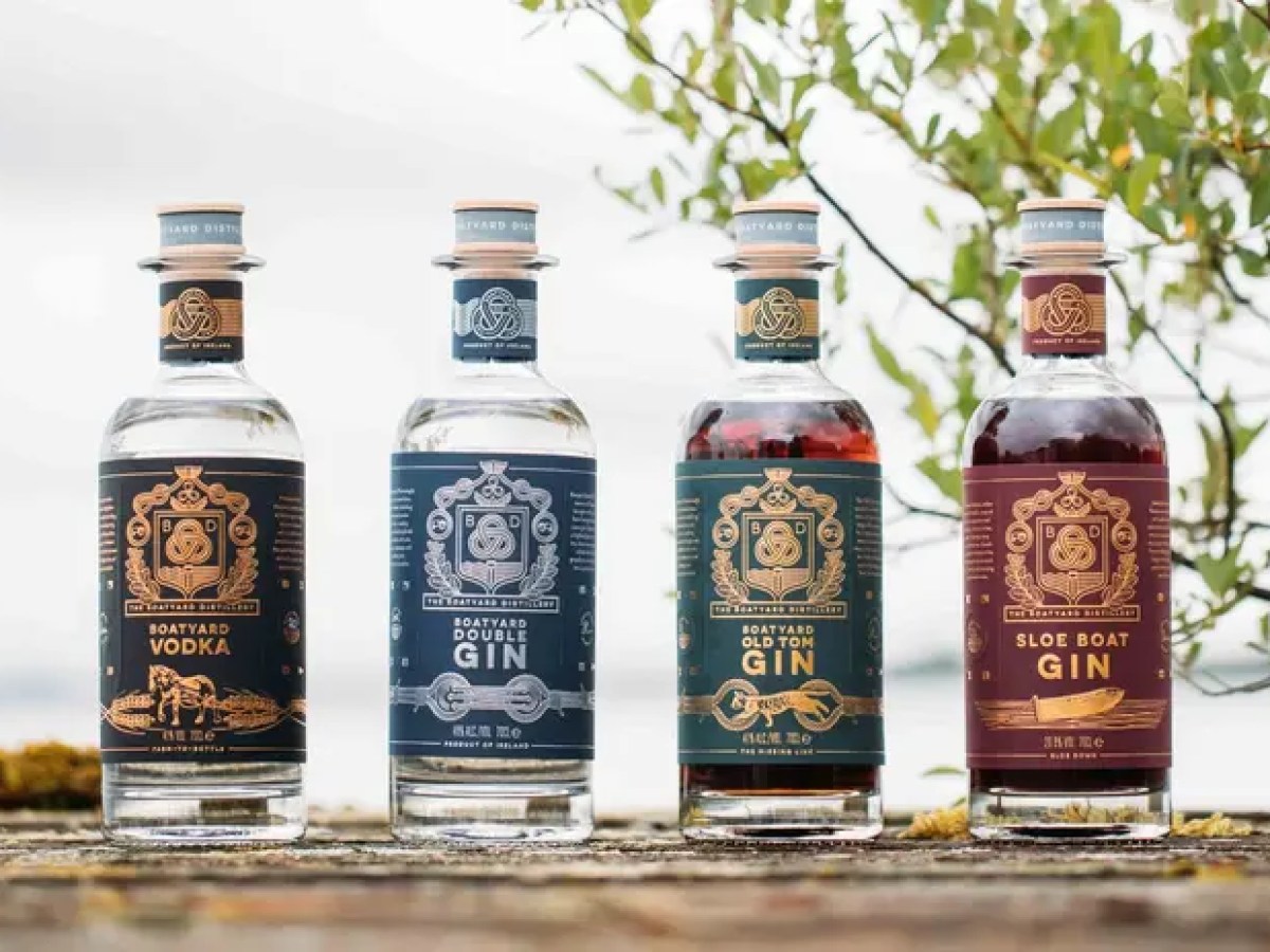 Four bottles of flavored spirits on a wooden surface with trees in the background.